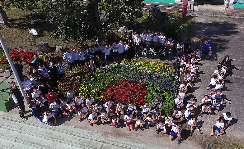 写真:咲き揃ったFBC花壇を囲んで全校で記念撮影。
